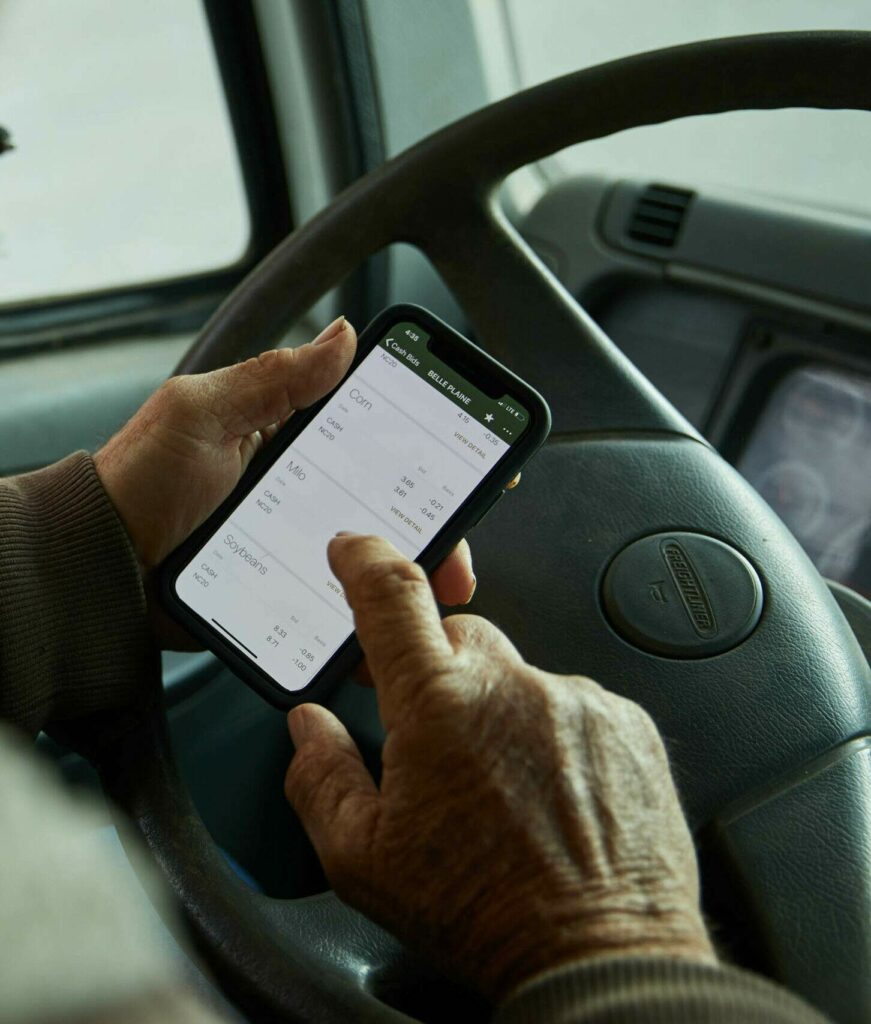 Man looking at a phone in front of a steering wheel while a truck is parked