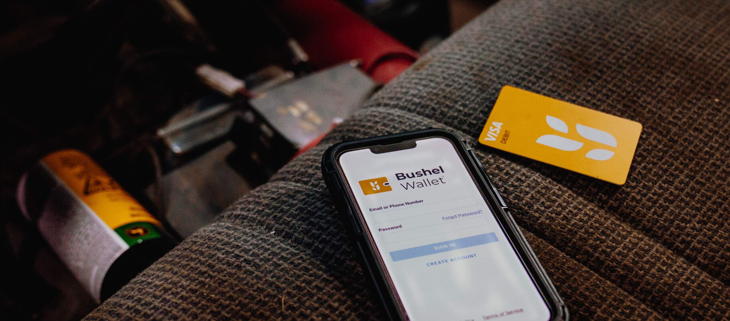 A phone showing Bushel Wallet on the screen sitting on the seat of a truck